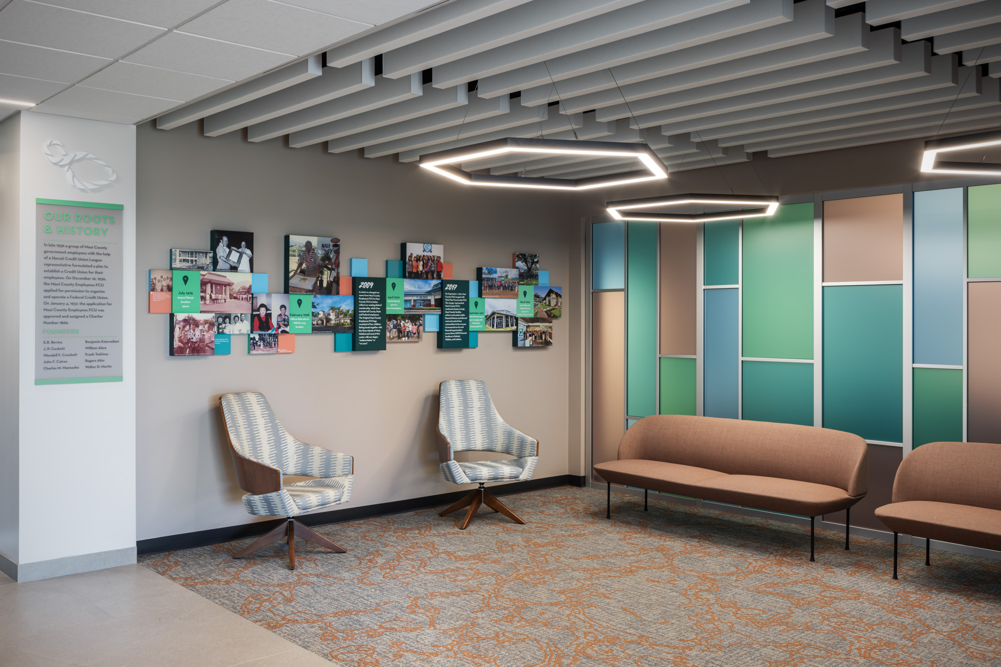 open waiting room space with furniture lining the wall as well as lighting fixtures hanging from the ceiling