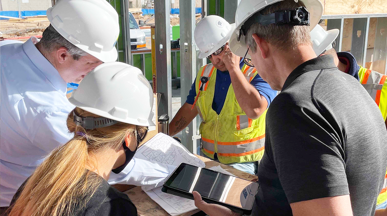 general contractor and two other team members looking over construction plans