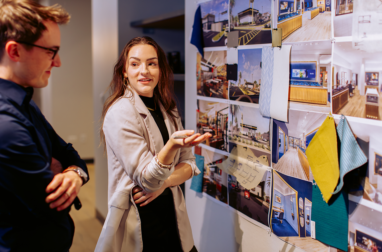 NewGround team members reviewing plans hanging on a wall and discussing what's new with a client