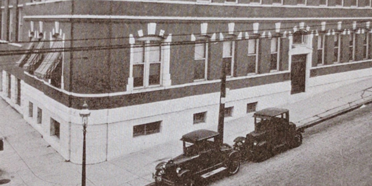 sepia toned photo of building with antique cars parked in front